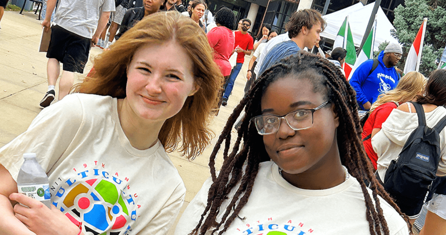 Two female students smile outdoors.
