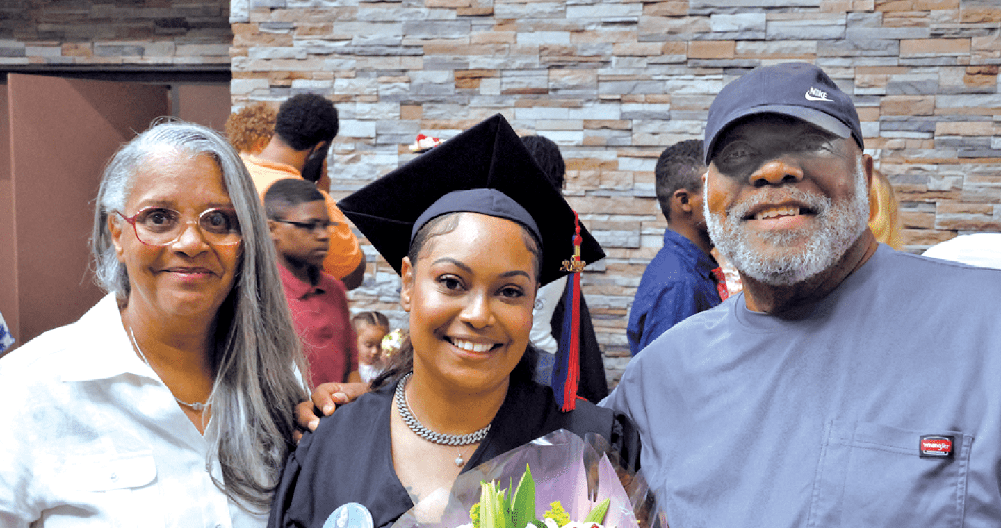 Student with cap and gown on with parents