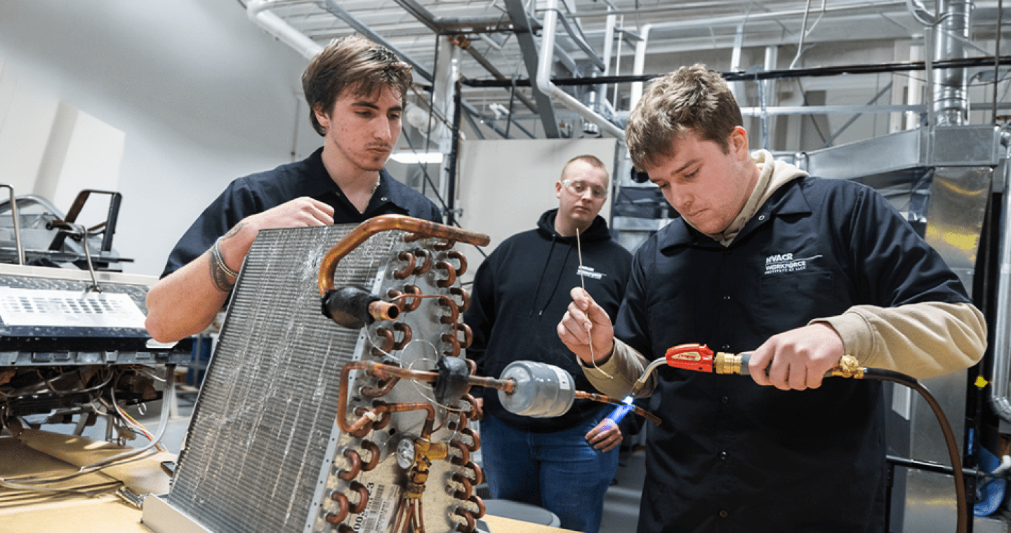 A student using a blow torch while other students watch