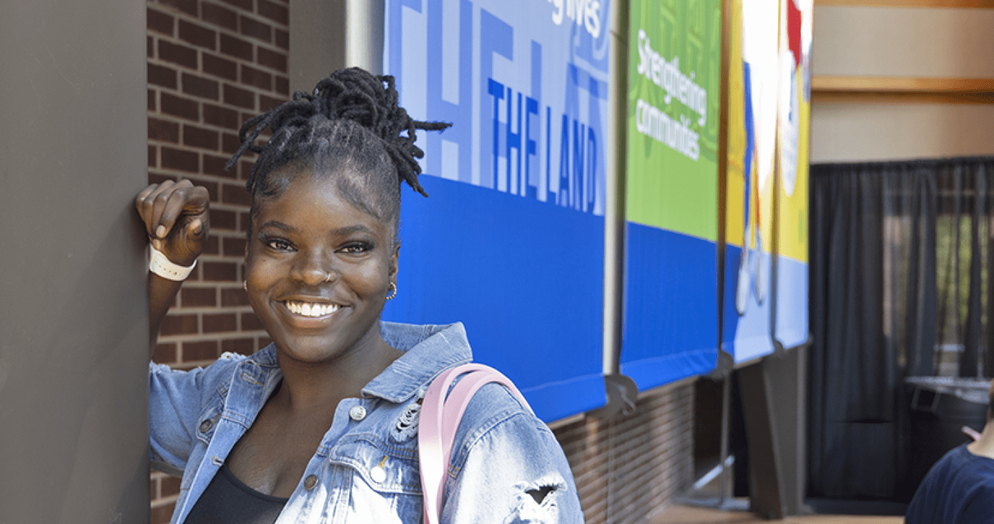 Student smiling with hand on a post