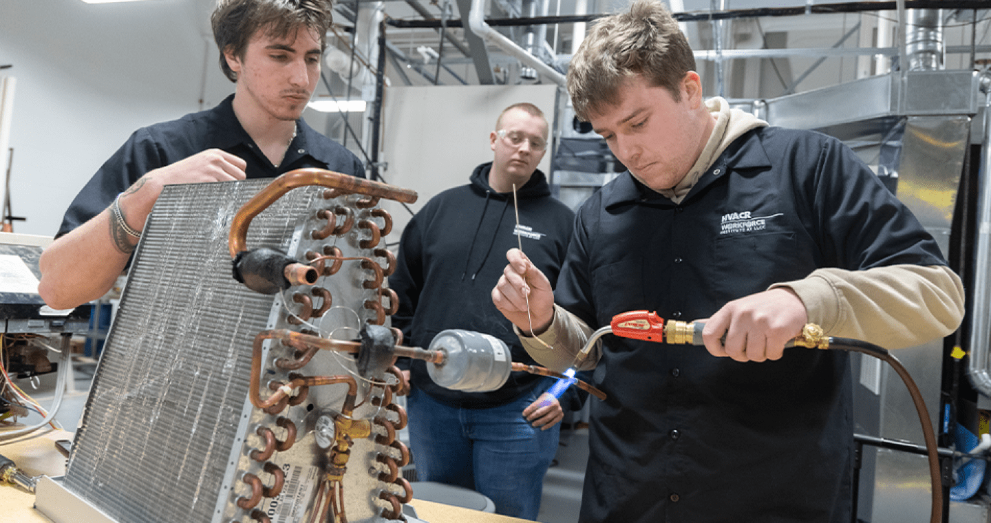 student using a blow torch while other students look on