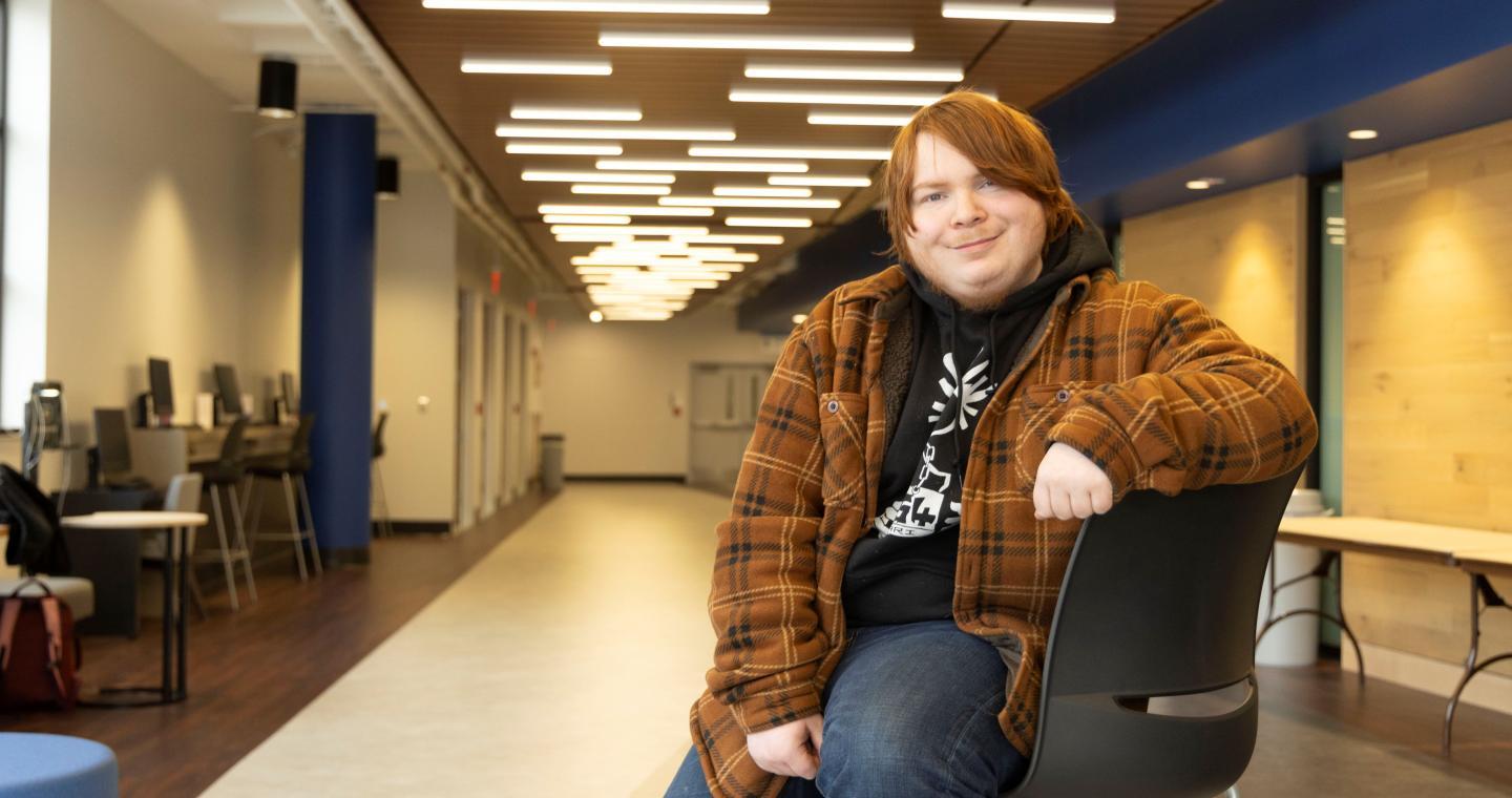 Student on a chair in the Menard Atrium