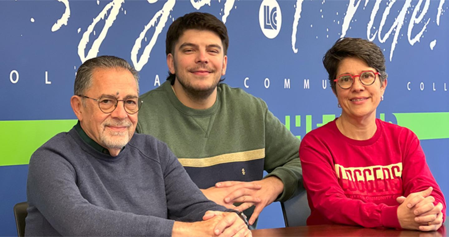 A father, son, mother seated in front of a wall that says LLCC Logger Pride