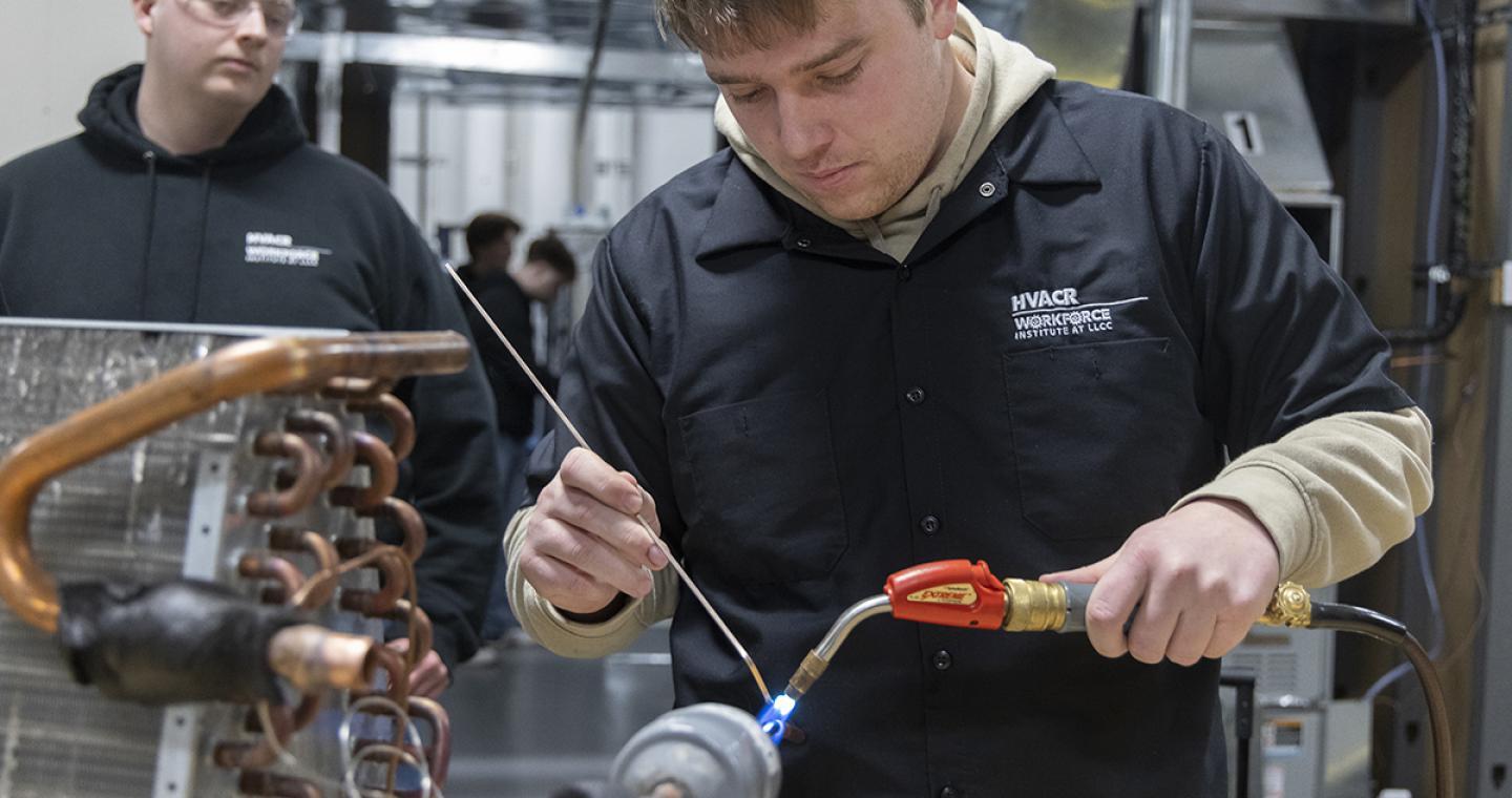 An HVAC student using a torch while another student watches