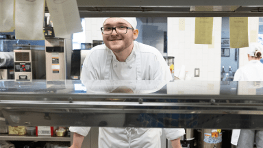 student chef in kitchen smiling at camera