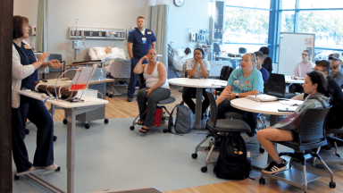 Faculty talking with students in nursing skills lab