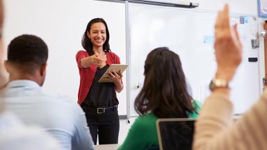 Teacher standing in front of classroom, calling on a student to answer