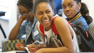 Three students sitting at table, closest one laughing