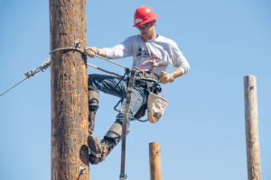 An electrical distribution lineman student climbs a pole.