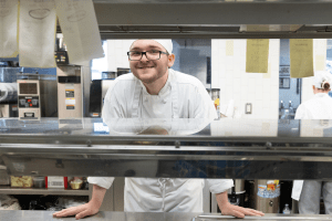 student chef in kitchen smiling at camera