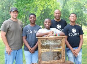 The Outlet of Springfield students standing next to a beehive.