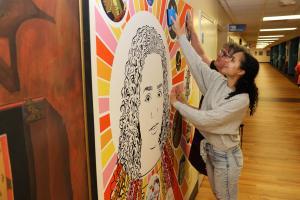 Divina Kluge putting her Integrated Media Design project on the wall in Menard Hall.