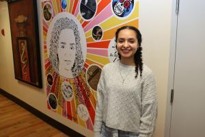 Divina Kluge posing by her capstone artwork