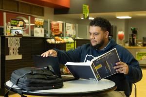 Student reading a text book sitting in a public study space.