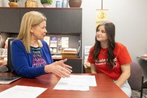 Two women sit and discuss writing a resume.