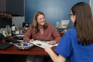 A staff member and student sit in an office and talk.