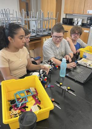 Three students in lab working on robotics project with LEGOS.