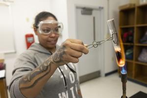 student with protective eye gear holding a test tube over a flame