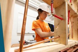 student working on plumbing