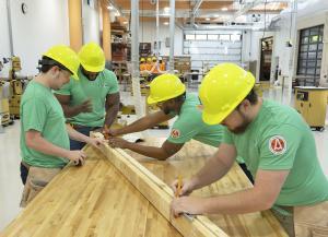 students wearing hard hats measuring a piece of wood