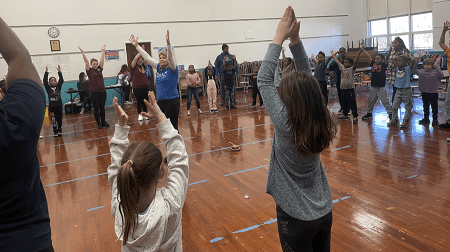 Dr. Yvonne Cosentino guides elementary school students through a yoga pose.