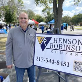 Person standing with sign for Henson Robinson
