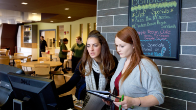 Two women review information on a computer at the front of Bistro Verde cafe in Workforce Careers Center.